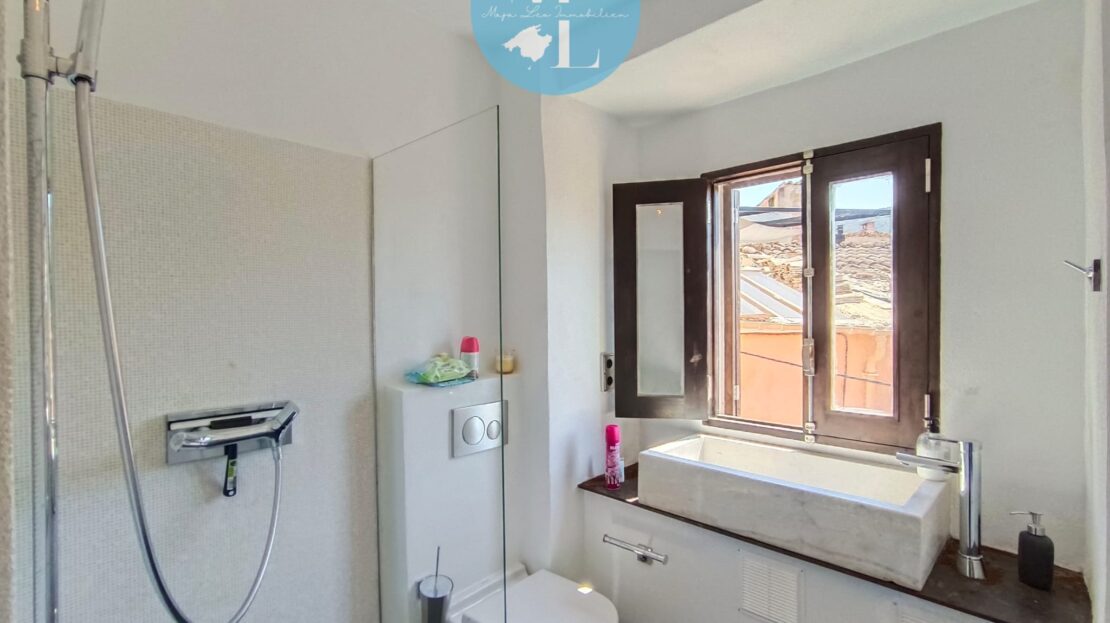 Helles Badezimmer mit Dusche, Toilette und Waschbecken, ausgestattet mit einem Fenster für Tageslicht.