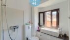 Helles Badezimmer mit Dusche, Toilette und Waschbecken, ausgestattet mit einem Fenster für Tageslicht.