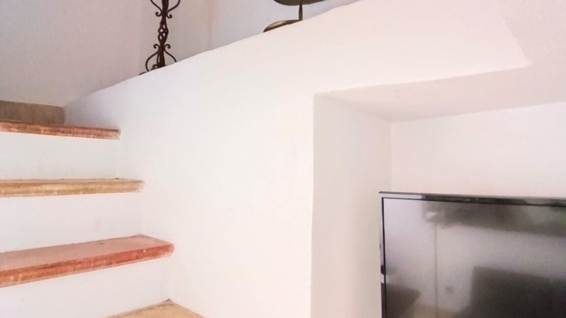 Treppenaufgang mit Holzstufen und einem Fernseher in einer Nische an der Wand.