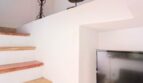 Treppenaufgang mit Holzstufen und einem Fernseher in einer Nische an der Wand.