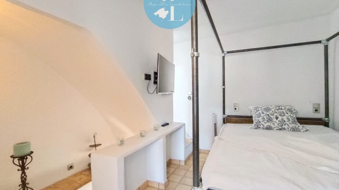 Ein Schlafzimmer mit einem Himmelbett, einem Fernseher an der Wand und einem kleinen Tisch.