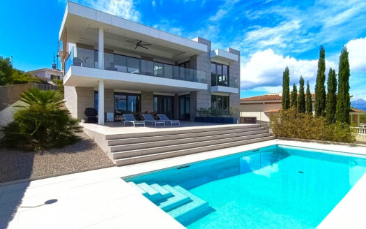 Moderne Villa mit Pool und Terrasse in Santa Ponsa, Mallorca, umgeben von Bäumen und einem klaren Himmel.