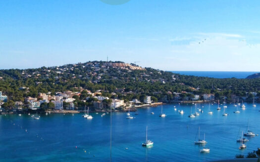 Widok na wybrzeże Santa Ponsa z jachtami na wodzie i pagórkowatym krajobrazem w tle.